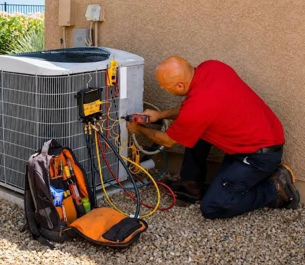 HVAC service professional using tools and gauges beside an outdoor condenser