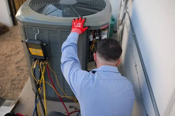 HVAC service professional checking an outdoor unit in a narrow side yard